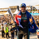 A photo of Mitch Evans on the podium in Jakarta with a New Zealand flag draped over his shoulders.
